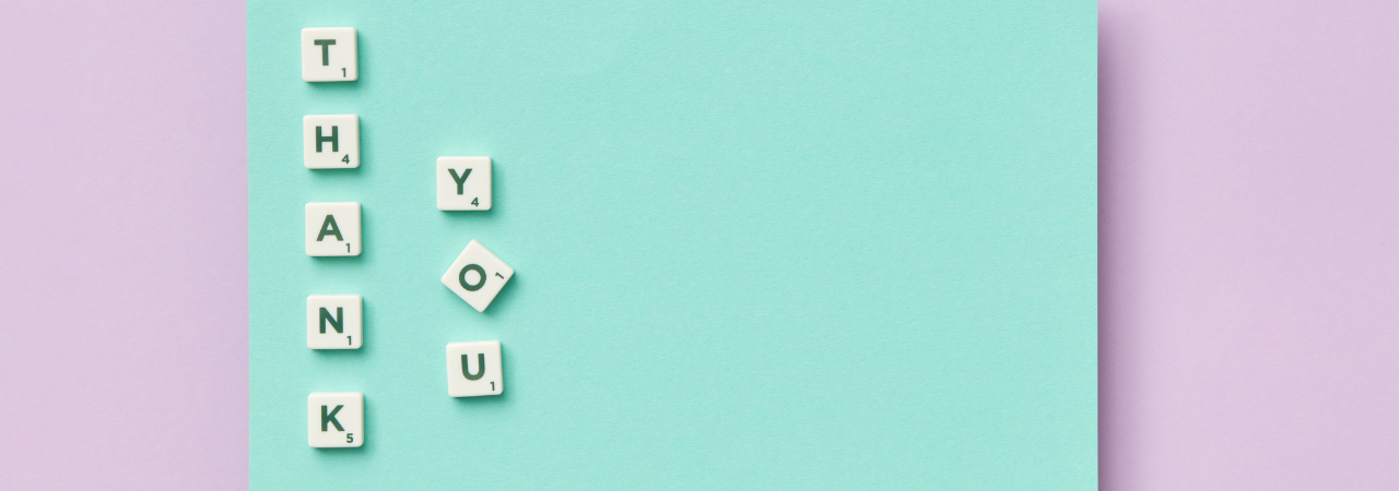 Pink background with light blue central block, and scrabble tiles spelling out 'thank you' vertically