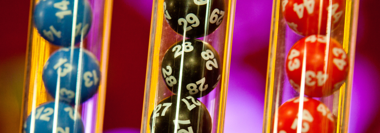 Close up of clear tubes containing numbered lottery balls in blue, black and red