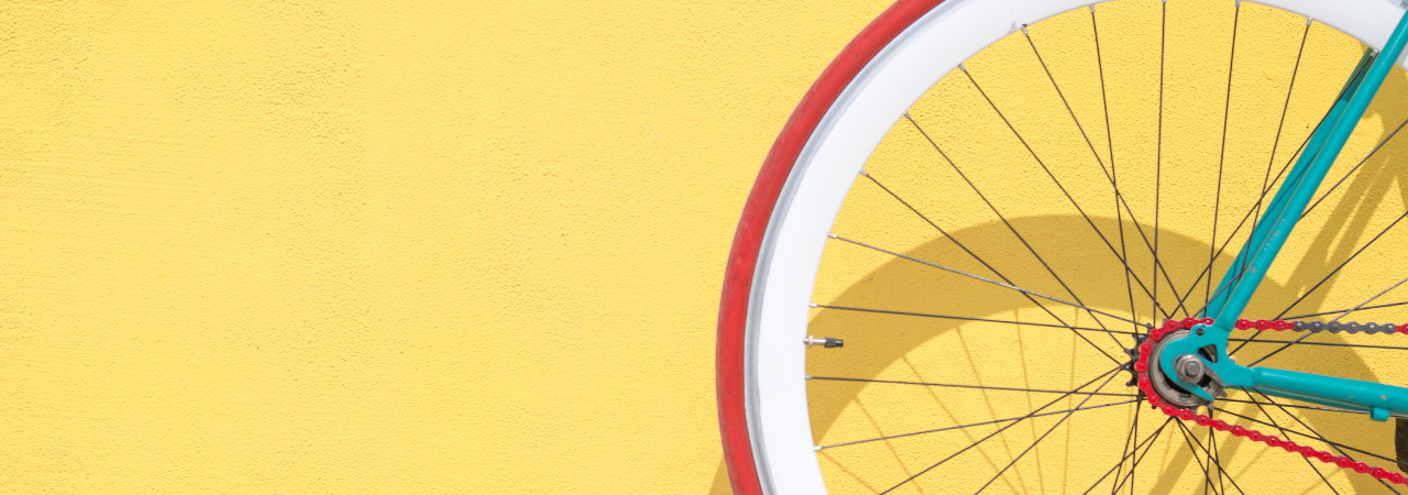 Yellow background with red and white bike wheel in foreground