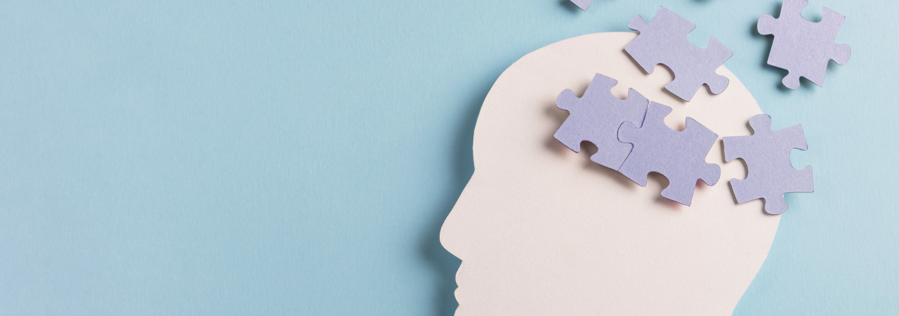 Side profile of paper face with jigsaw pieces spilling out of the top of the head, against light blue background