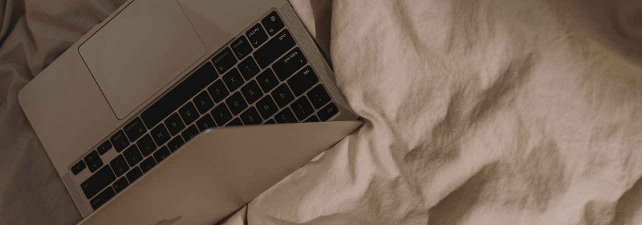 close up of silver laptop opened, framed at an angle on a bed sheet